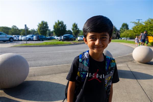 a boy student smiling in front of the parking lot